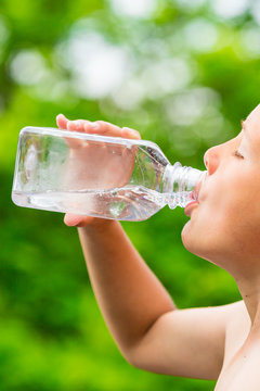 Boy drinking clean tap water from transparent plastic bottle
