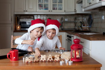 Two cute boys with santa hat, preparing cookies in the kitchen