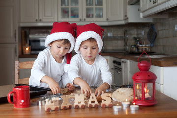 Two cute boys with santa hat, preparing cookies in the kitchen
