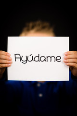 Child holding sign with Spanish word Ayudame - Help Me