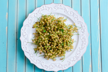 Fresh white currant on plate on rustic wooden turquoise background