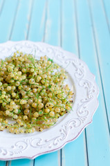 Fresh white currant on plate on rustic wooden turquoise background