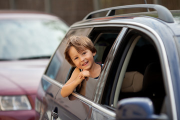 Fototapeta na wymiar Little cute child, boy, looking out the window of a car