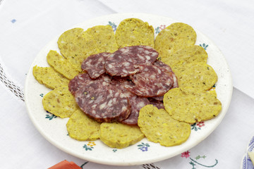 Dish of salchichon slices, typical spanish saussage, beside artisan sausage made of meat, eggs and several spices
