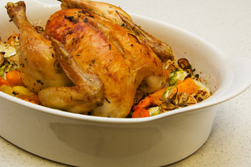 Appetizing chicken in herbs baked with vegetables in a big white dish