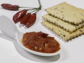 Salsa piccante di peperoncino con crackers su sfondo bianco