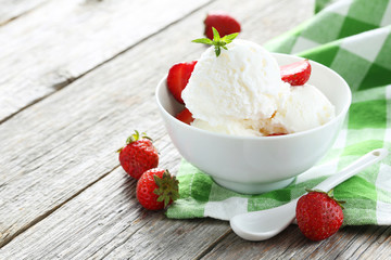 Ice cream in bowl with strawberries on grey wooden background