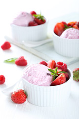 Ice cream in bowl with strawberries and raspberries on white woo