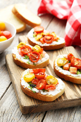 Tasty fresh bruschetta with tomatoes on cutting board on grey wo