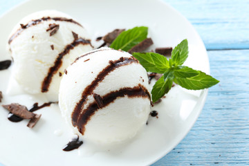 Sweet ice cream in plate on blue wooden background