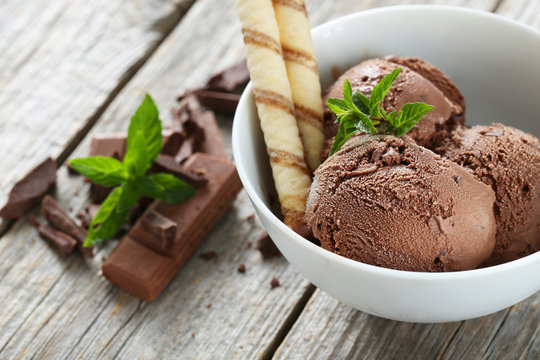 Sweet chocolate ice cream in bowl on grey wooden background