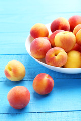 Fototapeta na wymiar Fresh apricots in plate on a blue wooden background