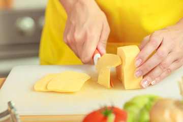 Woman hands cutting piece of cheese - obrazy, fototapety, plakaty