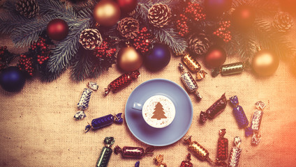 Obraz na płótnie Canvas Hot cappuccino with christmas tree shape on a table near pine br