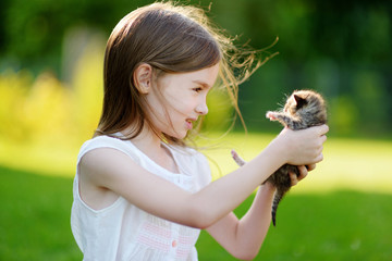 Adorable little girl playing with small kitten © MNStudio