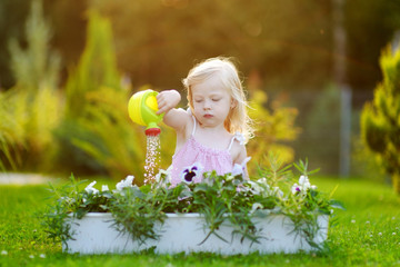 Cute little girl watering flowers in the garden © MNStudio