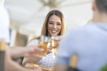 Beautiful young woman toasting with group of her friends at the outdoor cafe