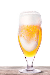 Frosty glass of light beer on a wooden table