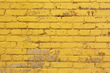 painted yellow brick wall background texture in bright tints. Aged street wall backdrop, texture
