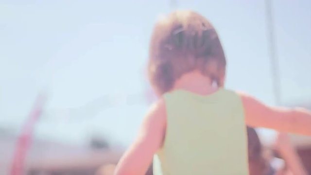 A girl struggles to push her older sister on a swingset

