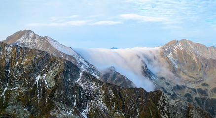 Morning fog crawling over rocky mountain ridge. Romania.