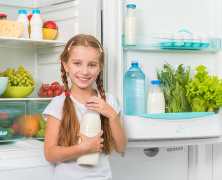 Little Girl Holding Milk Near Fridge