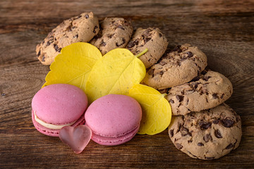 cookies and pink macaron with yellow leaves on wood