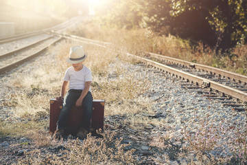 niño con maleta en las vías del tren 