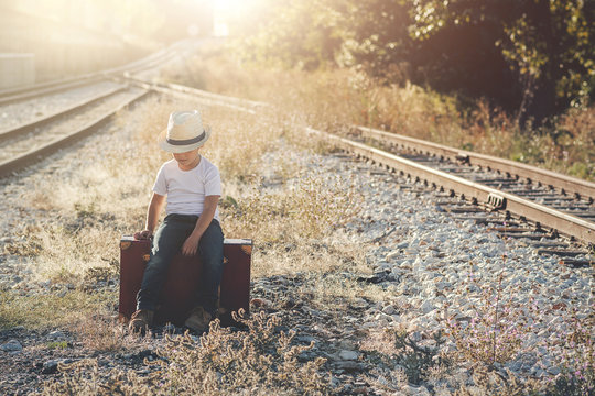 ni&ntilde;o con maleta en las v&iacute;as del tren 