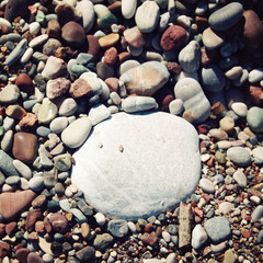 Big round white stone amongst grey and brown pebbles on the beac