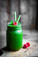 Fresh green smoothie on rustic wooden background