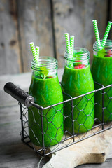 Fresh green smoothie on rustic wooden background