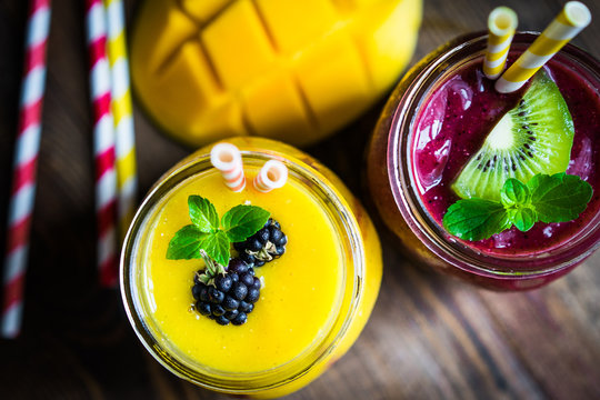 Colorful two layer smoothies with mango and berries on rustic wo