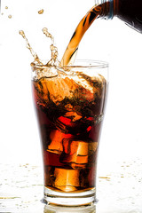 Pouring cola into glass with ice cubes