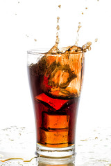 Fototapeta na wymiar Ice cube droped in cola glass and cola splashing