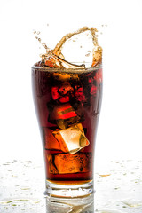 Ice cube droped in cola glass and cola splashing