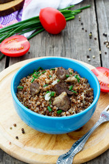 Buckwheat with meat and tomatoes on a wooden background