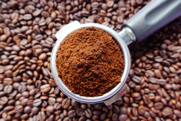 Freshly ground coffee beans in a metal filter on coffee beans background 