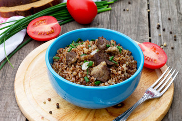 Buckwheat with meat and tomatoes on a wooden background