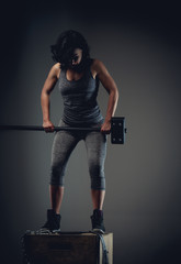 Sporty woman in grey sportswear standing on wooden box.