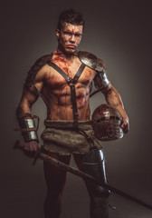 Fototapeta na wymiar Muscular bloody gladiator with sword and helmet.