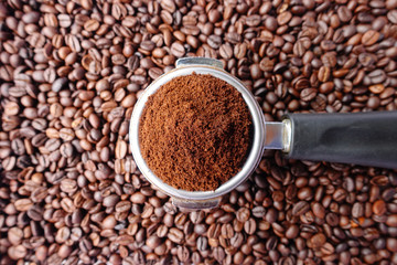 Freshly ground coffee beans in a metal filter on coffee beans background 