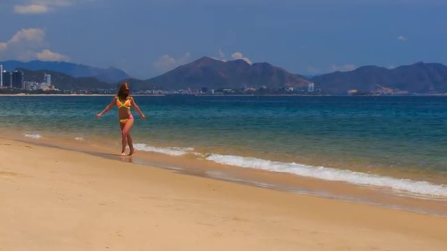 blonde slim girl in bikini makes shoulder circle on sand beach
