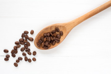 Coffee  beans on a spoon and wooden background