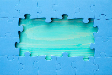 Puzzle pieces arranged as a border around a green wooden surface