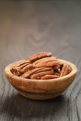 pecan nuts in olive wood bowl on oak table