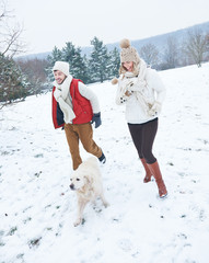 Paar mit Hund geht im Winter spazieren