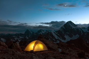 Twilight Mountain Panorama and Tent Illuminated Camping Yellow Tent Night High Altitude Alpine Landscape Crescent in Dark Blue Sky warmer tone