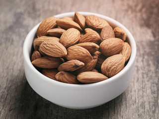 almonds in white bowl on wood table