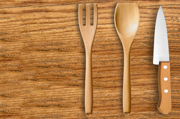 wooden spoon, fork and knife on cutting board isolated on white